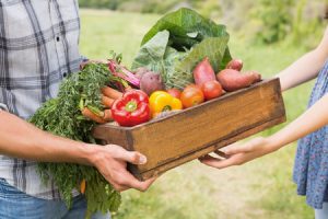 Farmer giving box of veg to customer on a sunny day